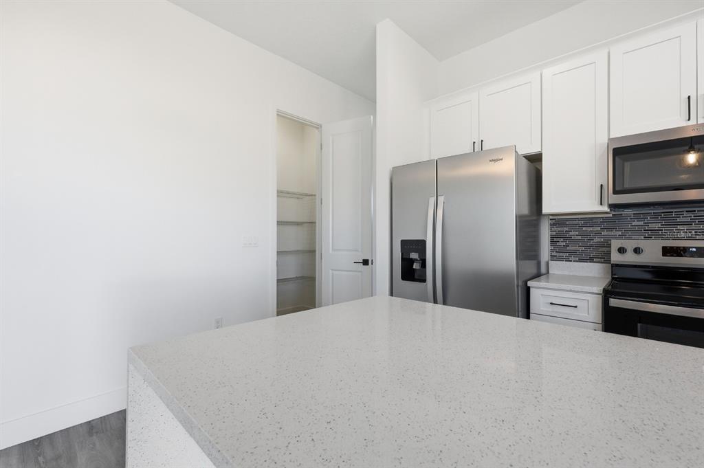 An open-concept living area with light wood-look flooring, white walls, and a modern kitchen — 17181 SW 20TH COURT ROAD, OCALA, FL