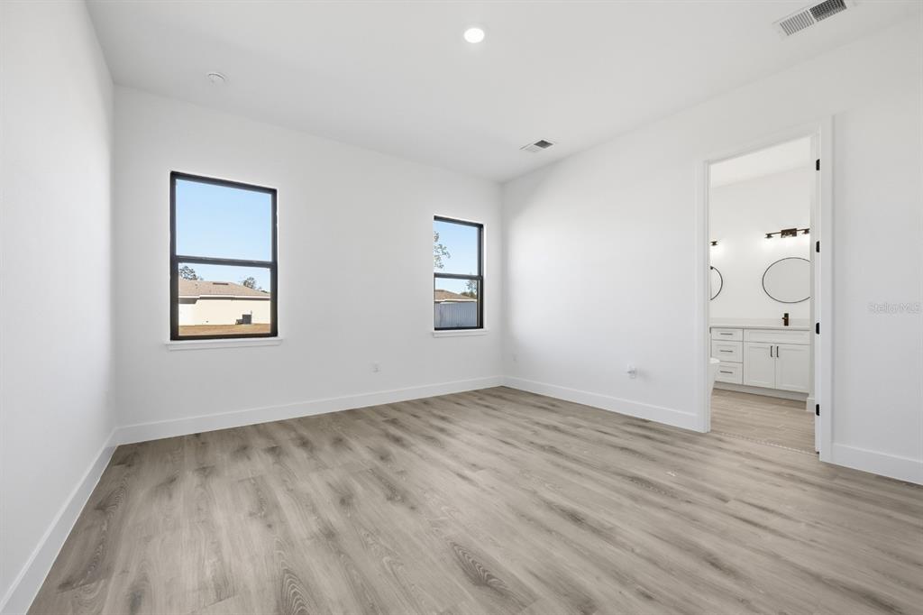 A modern kitchen features white cabinets, quartz countertops, stainless steel appliances, and a large island — 17181 SW 20TH COURT ROAD, OCALA, FL