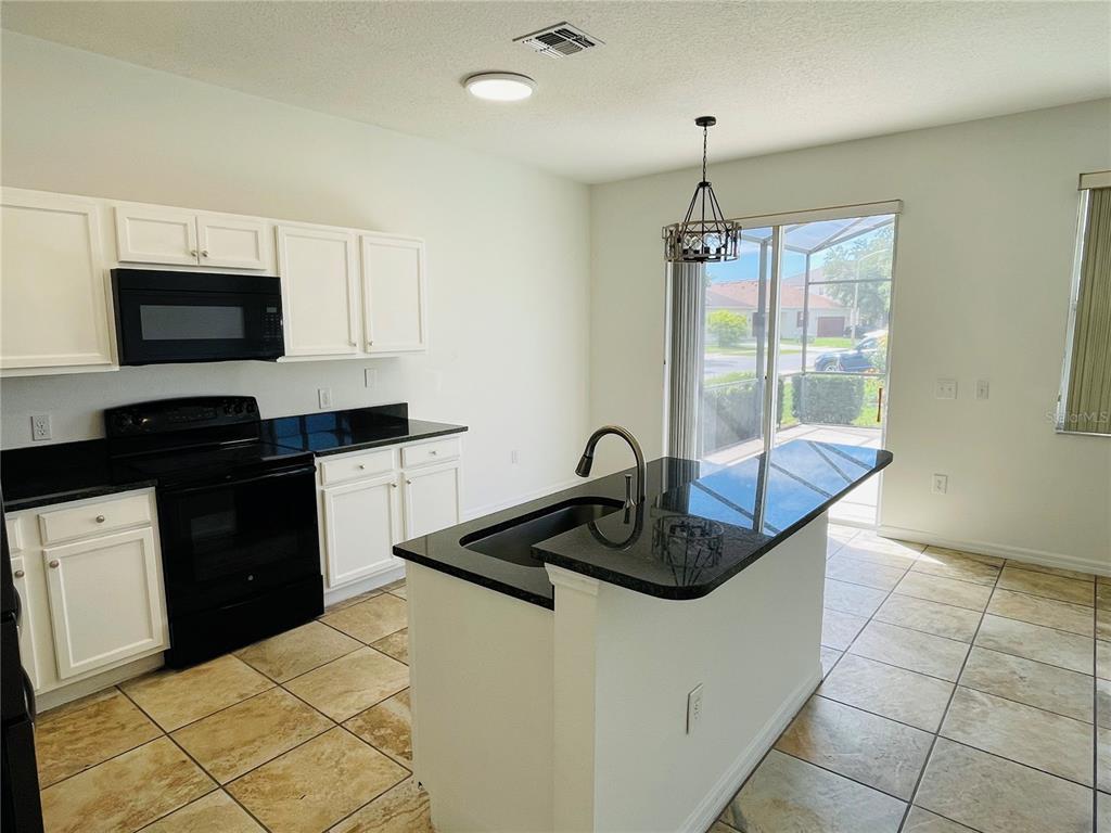 A kitchen with white cabinets, black appliances, granite countertops, and a center island — 2728 PORTCHESTER COURT, KISSIMMEE, FL
