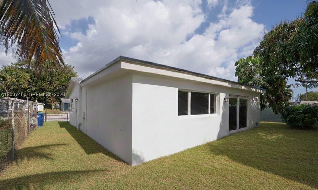 A white, single-story house exterior with a flat roof and a grassy backyard — 3460 NW 17th St, Lauderhill FL 33311, LAUDERHILL, FL