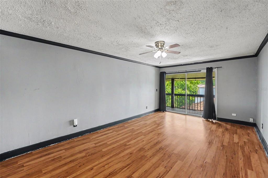 A room with gray walls, dark trim, wood-look flooring, a ceiling fan, and a sliding door — 6308 NEWTOWN CIRCLE UNIT C4, TAMPA, FL