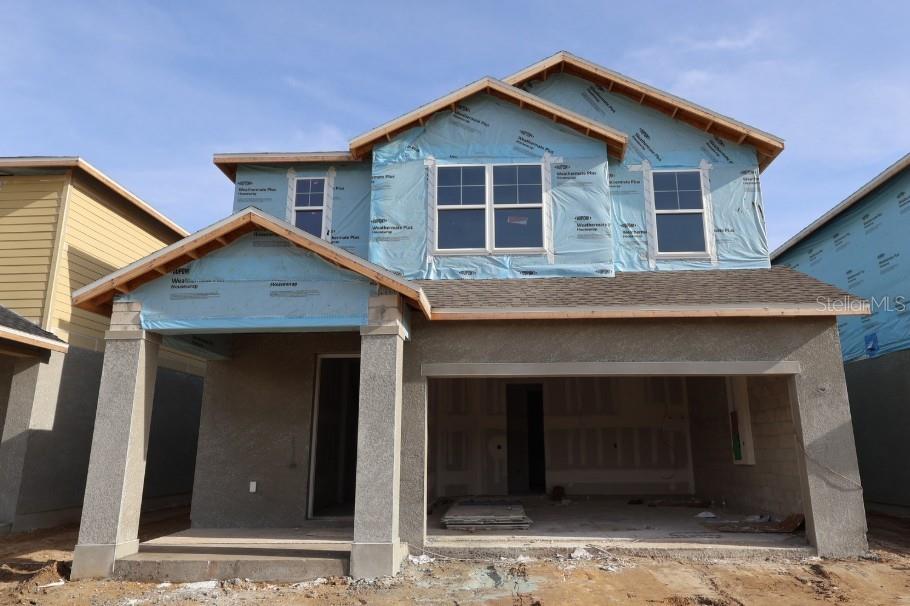 A two-story house exterior features a tan upper level, a gray lower level, and a garage — 3417 YELLOW CASSIA DRIVE, WESLEY CHAPEL, FL