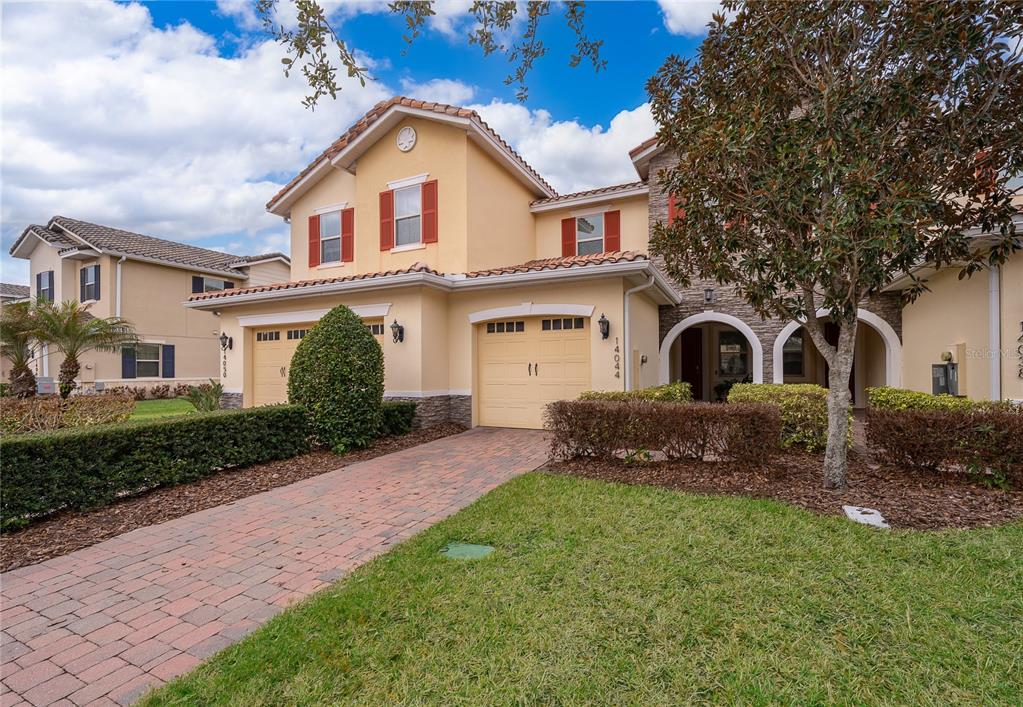 A two-story suburban house with a brick driveway, two-car garage, and arched entryway — 14044 MILLINGTON STREET, ORLANDO, FL