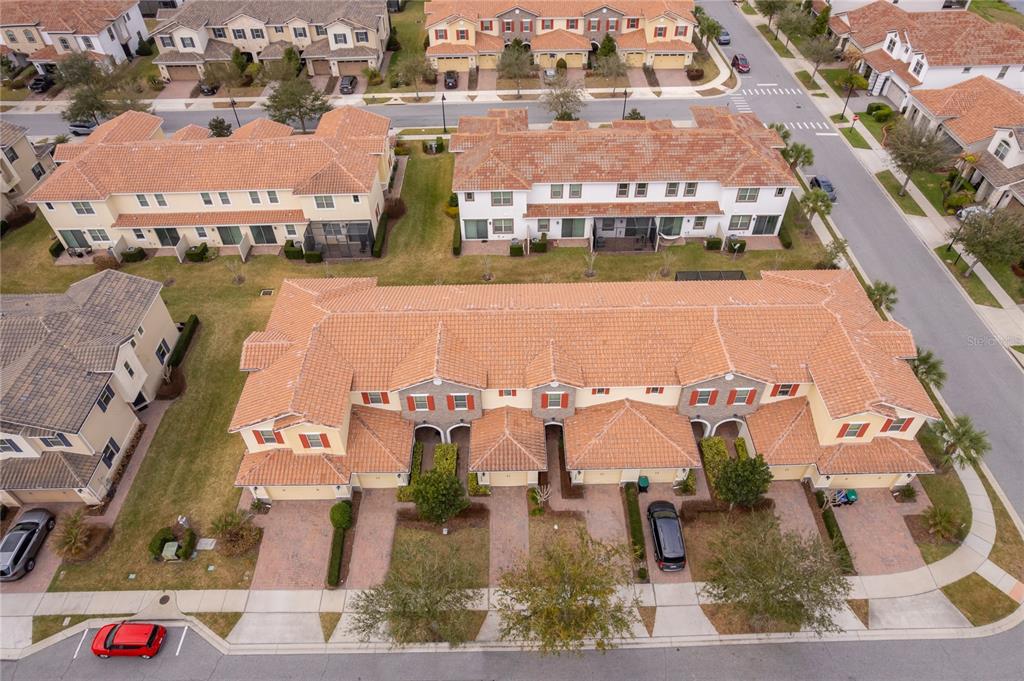 An aerial view shows several multi-story townhomes with terracotta tile roofs and paved driveways — 14044 MILLINGTON STREET, ORLANDO, FL