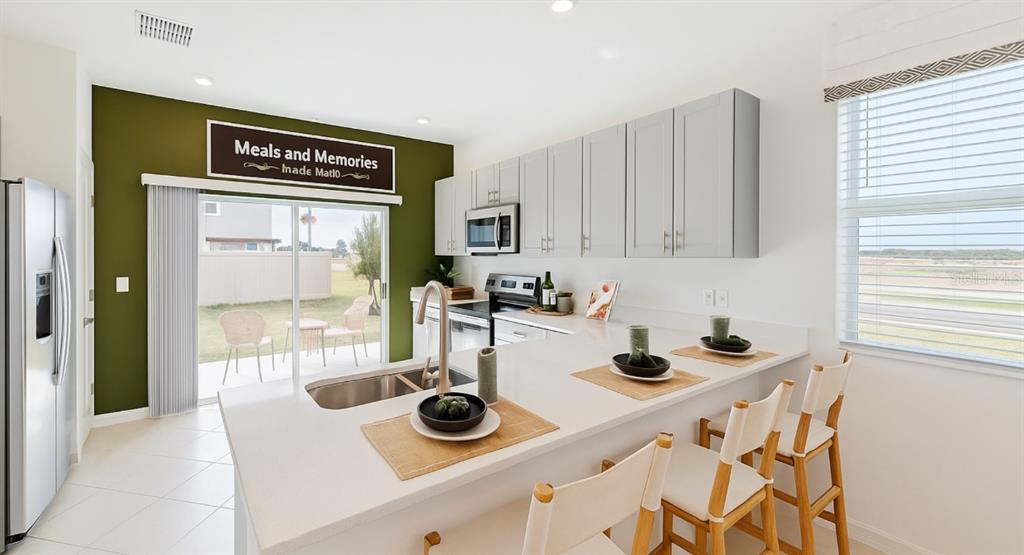 A kitchen features white countertops, light gray cabinets, and an olive green accent wall — 2004 VIEWFINDER STREET, KISSIMMEE, FL