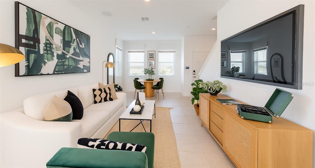 A living room with a white sofa, a television, and a dining area with windows — 2004 VIEWFINDER STREET, KISSIMMEE, FL