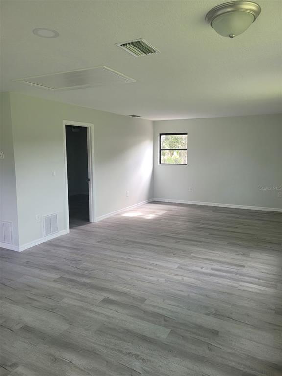 An empty room features light gray walls, wood-look flooring, a ceiling light, and a window — 2331 MISSION VALLEY BOULEVARD, NOKOMIS, FL