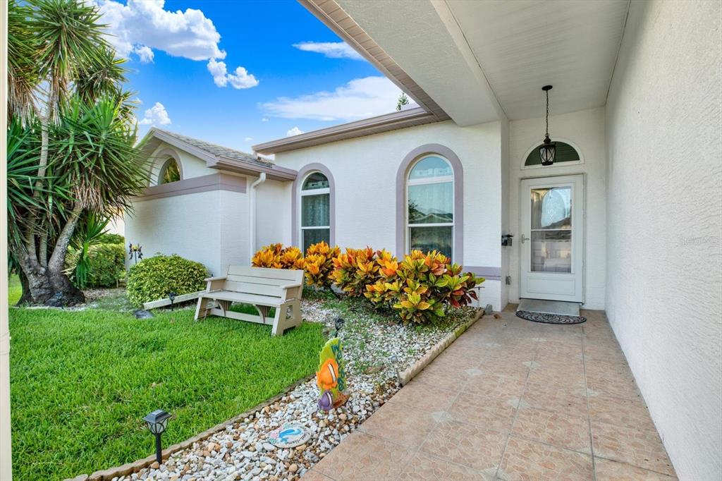 A front entryway features a tiled porch, a white door, and a landscaped garden bed — 5924 WILLOW CREEK COURT, NEW PORT RICHEY, FL