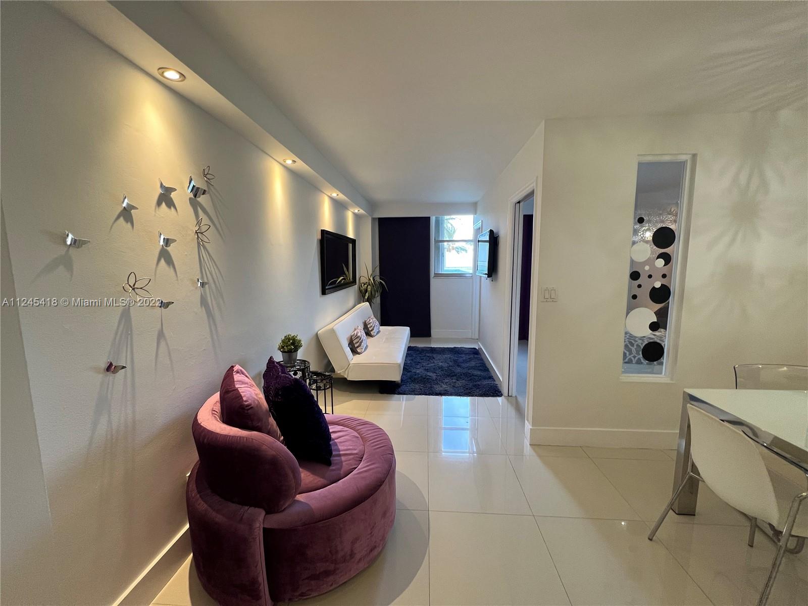 A living room features a purple circular chair, a white sofa, and tile flooring — 5161 Collins Ave # 309, Miami Beach FL 33140, MIAMI BEACH, FL