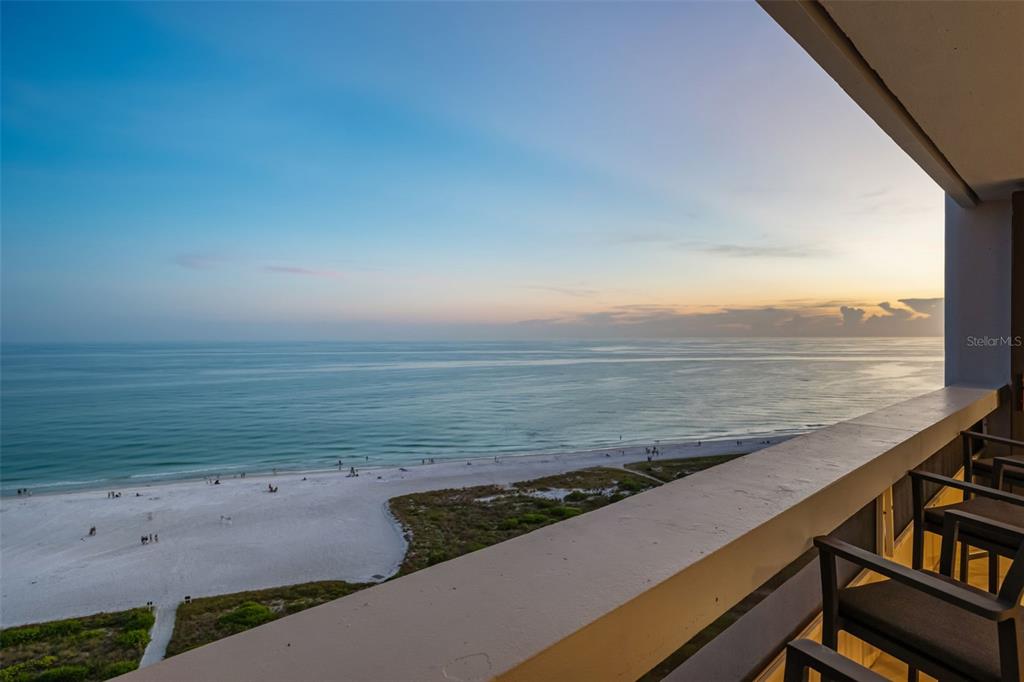 A high-angle view from a balcony overlooking a sandy beach and the ocean at sunset — 5400 OCEAN BOULEVARD UNIT #15 1-4, SARASOTA, FL