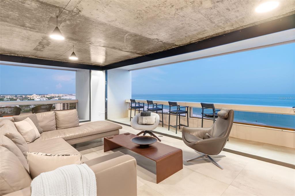 A modern living room features a concrete ceiling, large glass walls, and ocean views — 5400 OCEAN BOULEVARD UNIT #15 1-4, SARASOTA, FL