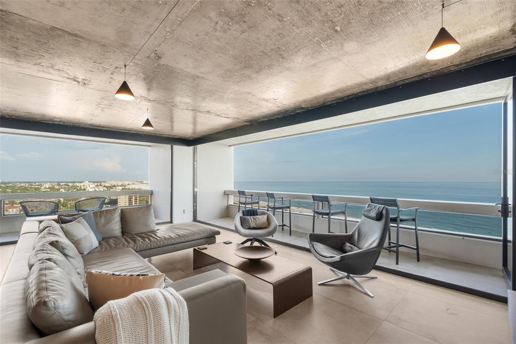 A modern living room with a concrete ceiling, large windows, and a balcony overlooking the ocean — 5400 OCEAN BOULEVARD UNIT #15 1-4, SARASOTA, FL
