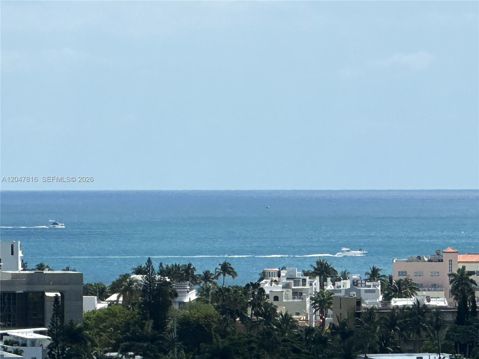An elevated view shows the ocean, boats, and surrounding buildings with palm trees — 1000 West Ave # 1532, Miami Beach FL 33139, MIAMI BEACH, FL