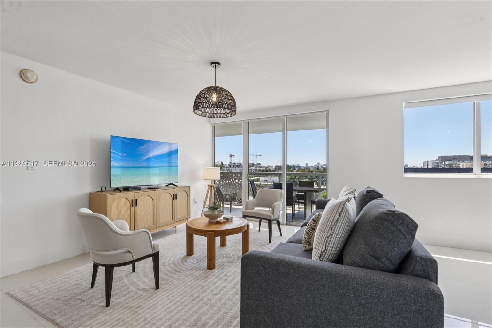 A living room features a gray sofa, a wooden coffee table, and a balcony view — 1100 100th St # 703, Bay Harbor Islands FL 33154, BAY HARBOR ISLANDS, FL