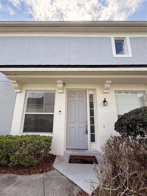 The exterior of a two-story townhouse features a gray front door and a small porch — 1178 SHALLCROSS AVENUE, ORLANDO, FL