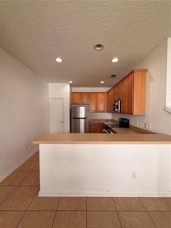 A kitchen features light wood cabinets, a stainless steel refrigerator, and a beige breakfast bar — 1178 SHALLCROSS AVENUE, ORLANDO, FL
