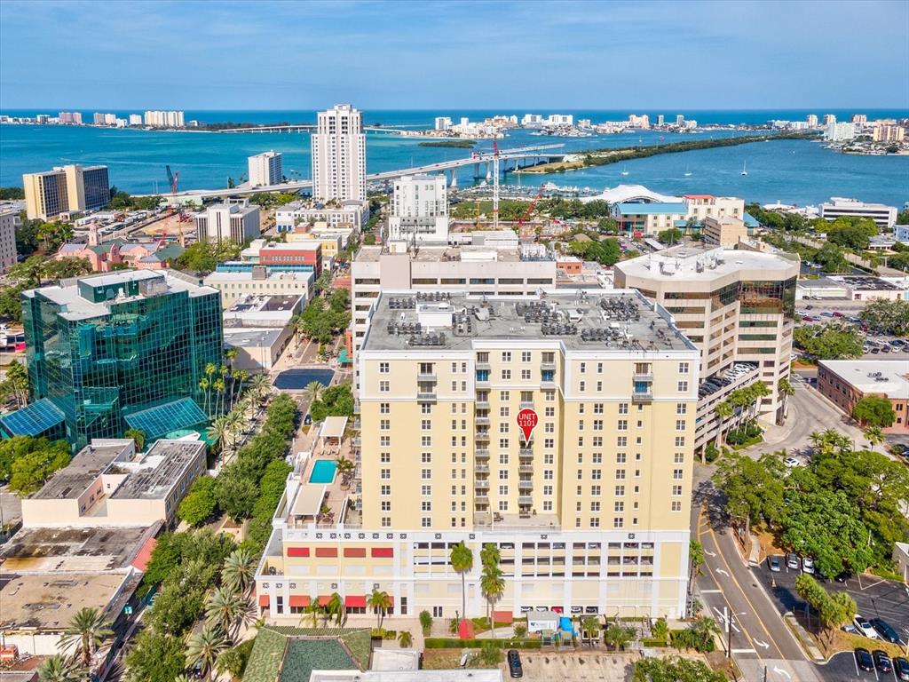 An aerial view shows a tall, tan residential building with a red location marker — 628 CLEVELAND STREET UNIT 1011, CLEARWATER, FL