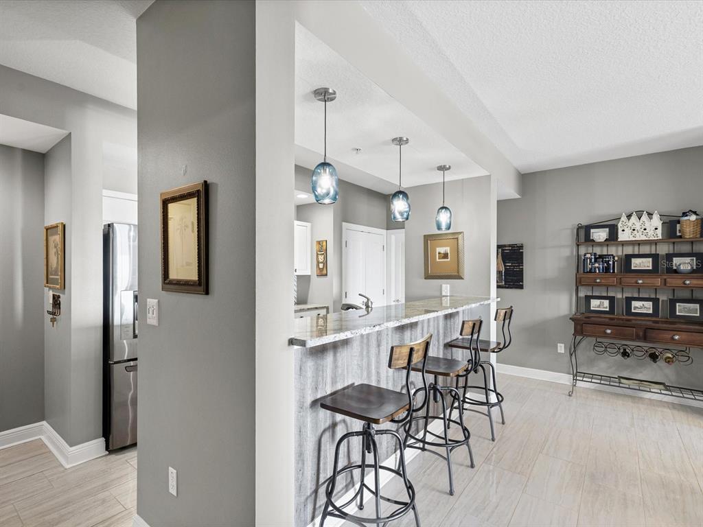 A kitchen breakfast bar with three stools, pendant lighting, and gray walls — 628 CLEVELAND STREET UNIT 1011, CLEARWATER, FL