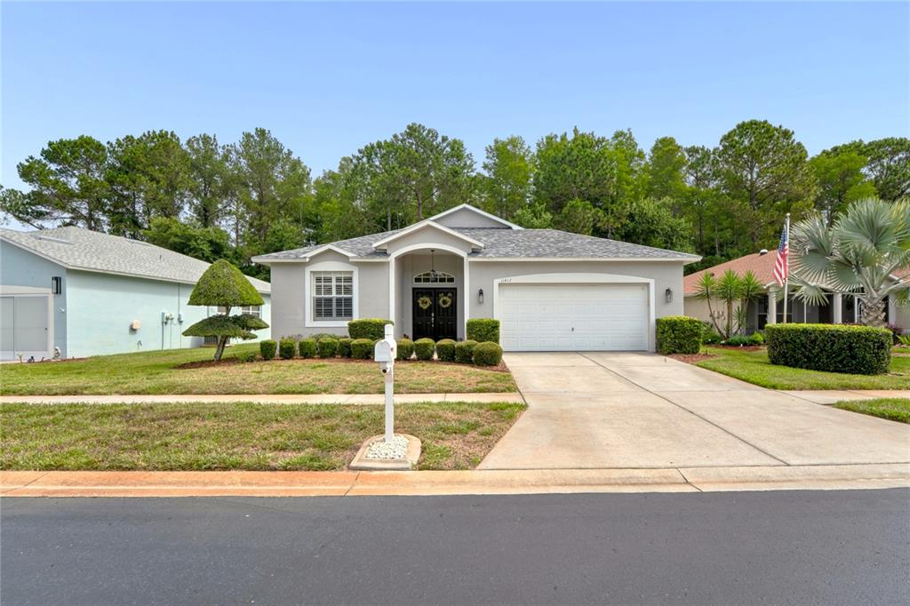 A single-story suburban house with a gray exterior, a two-car garage, and a manicured lawn — 11413 BLOOMINGTON COURT, NEW PORT RICHEY, FL