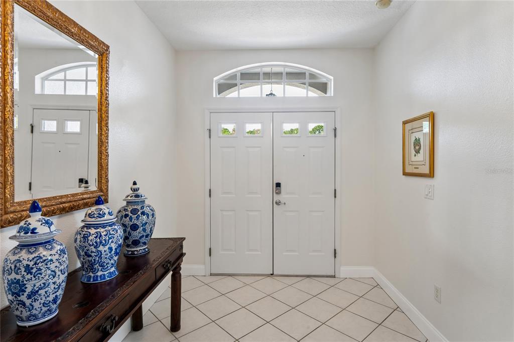 An entryway features a double door with a transom window, tiled floor, and console table — 11413 BLOOMINGTON COURT, NEW PORT RICHEY, FL