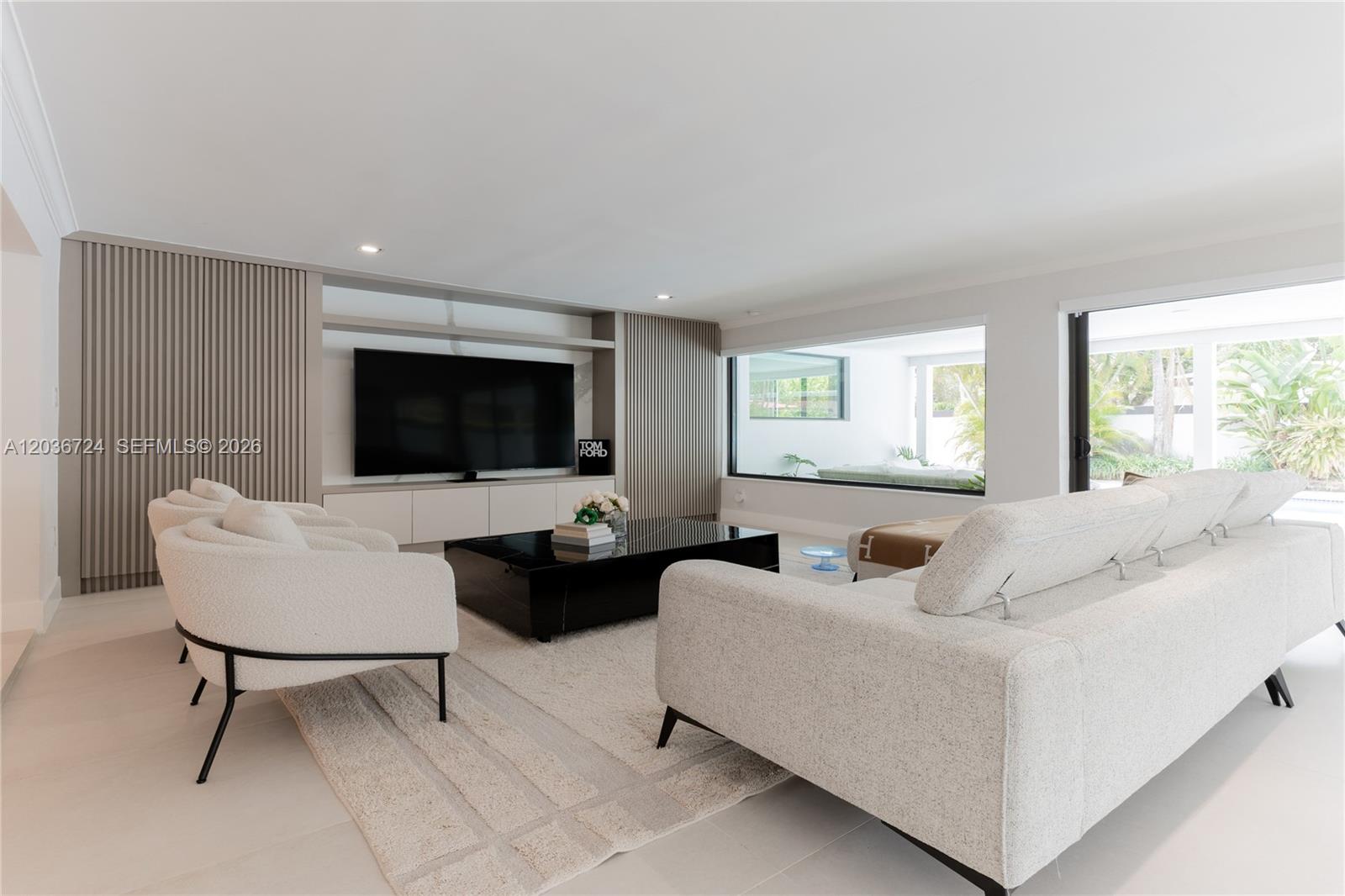 A modern living room features a large television, slatted wall panels, and white textured furniture — 7300 SW 77th Ave, Miami FL 33143, MIAMI, FL