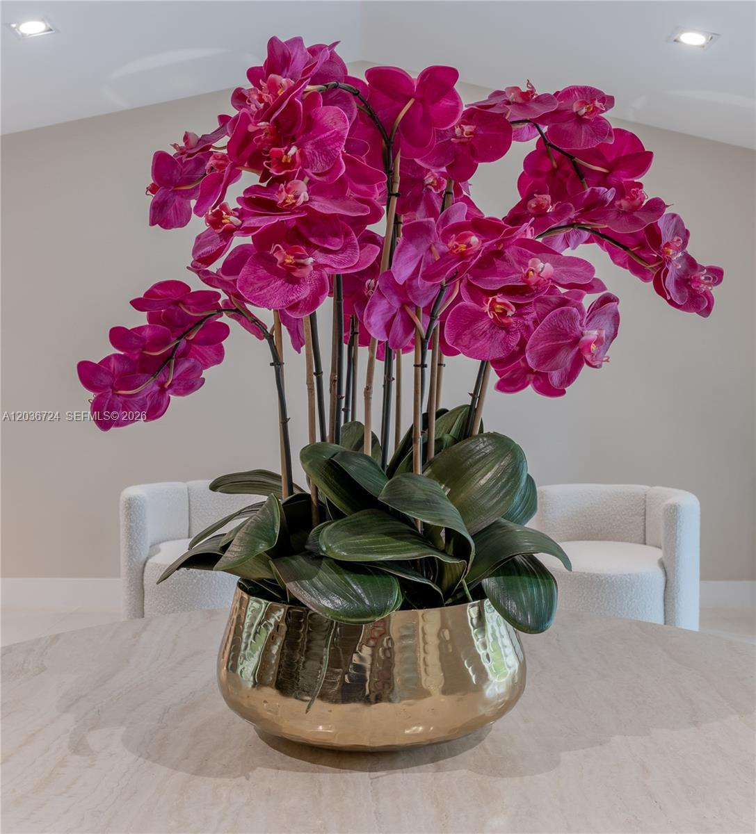 A large arrangement of magenta orchids sits in a gold bowl on a round table — 7300 SW 77th Ave, Miami FL 33143, MIAMI, FL