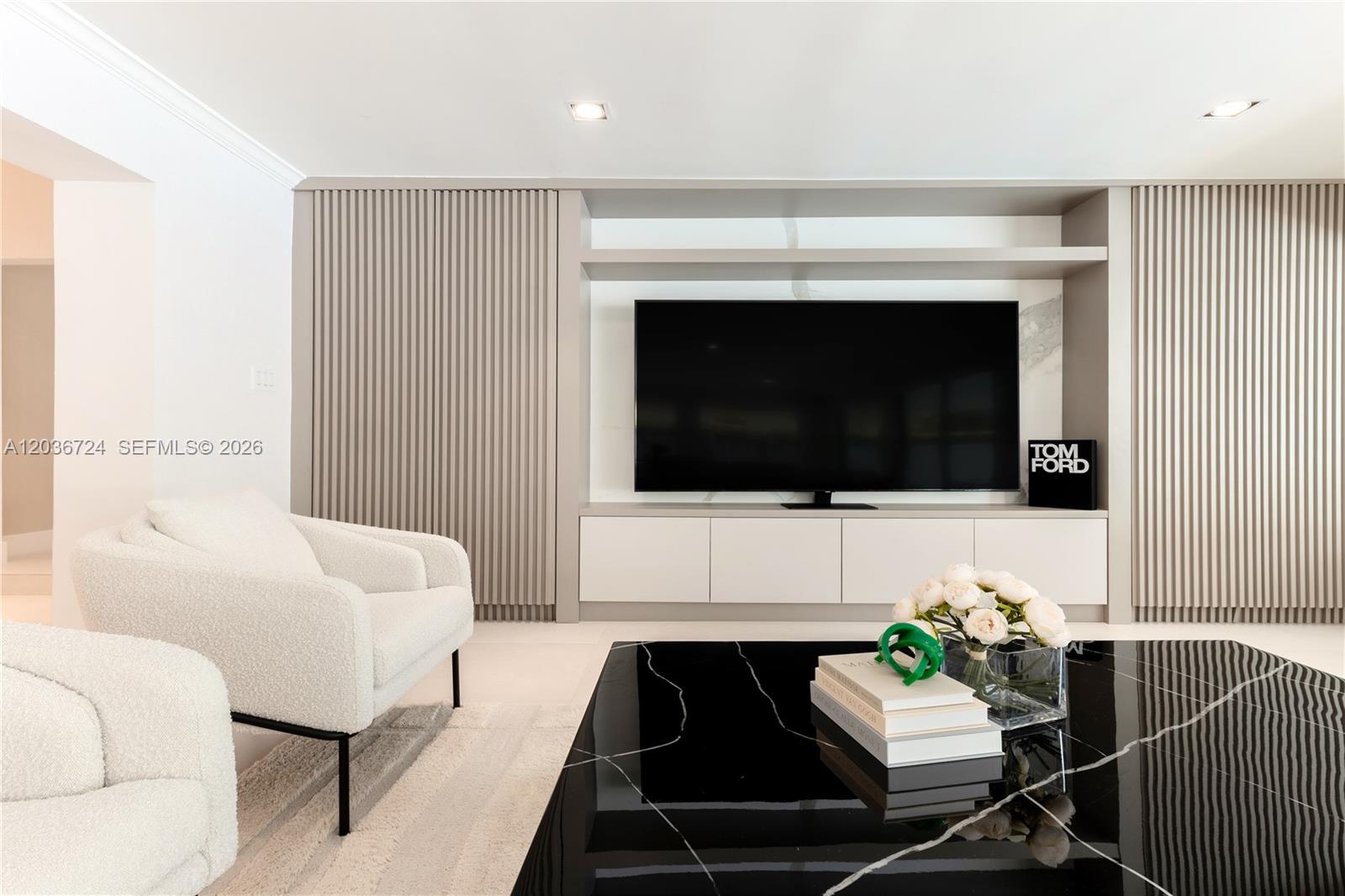 A modern living room features a wall-mounted television, slatted wood panels, and a black table — 7300 SW 77th Ave, Miami FL 33143, MIAMI, FL