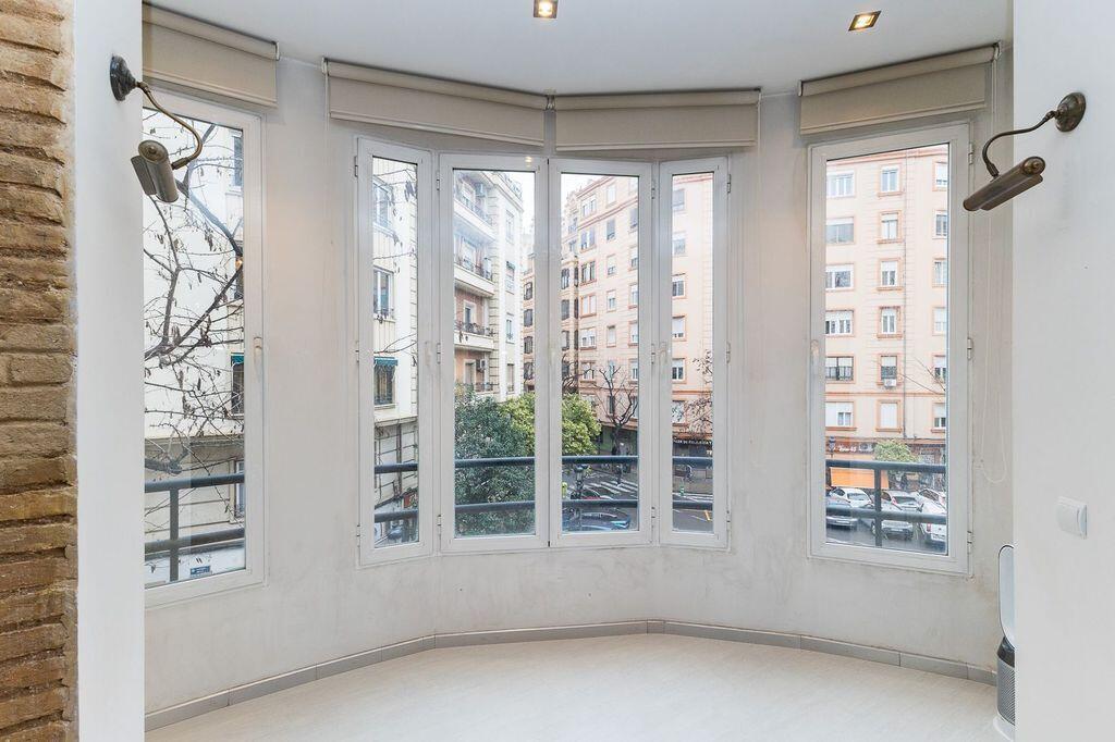 A bright room features a curved wall of windows overlooking a city street — 26 Carrer Del Mestre Gozalbo, FL