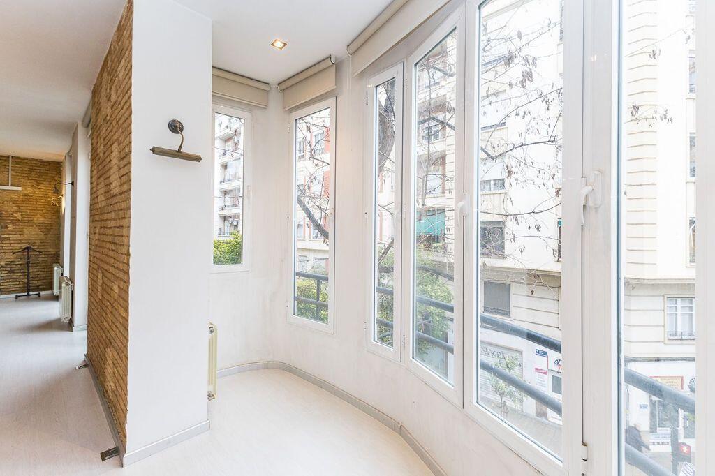 A bright room with a brick accent wall and large windows overlooking a city street — 26 Carrer Del Mestre Gozalbo, FL