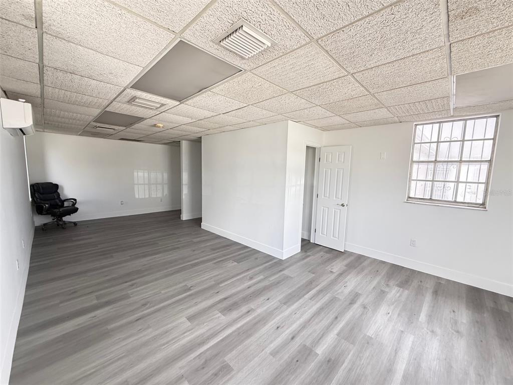 An empty office space features light gray wood-look flooring, white walls, and a drop ceiling — 14060 NW 19TH AVENUE, OPA LOCKA, FL