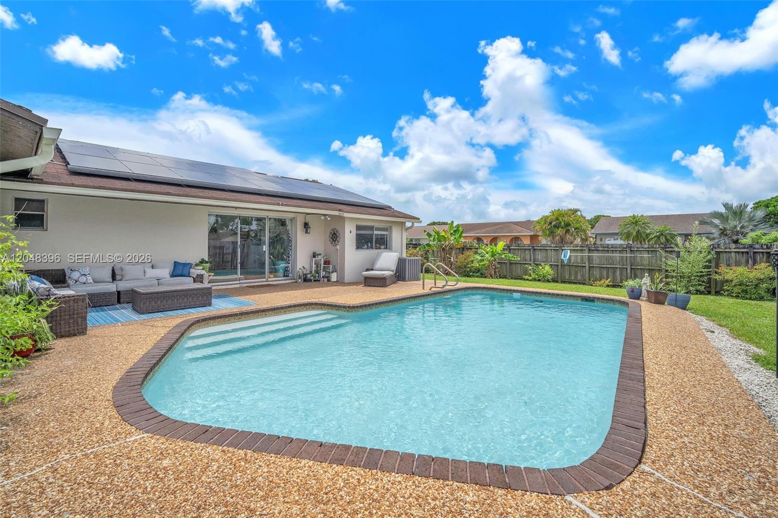 A backyard features a swimming pool with a brick border and a patio with furniture — 2401 NW 110th Ter # 2401, Sunrise FL 33322, SUNRISE, FL