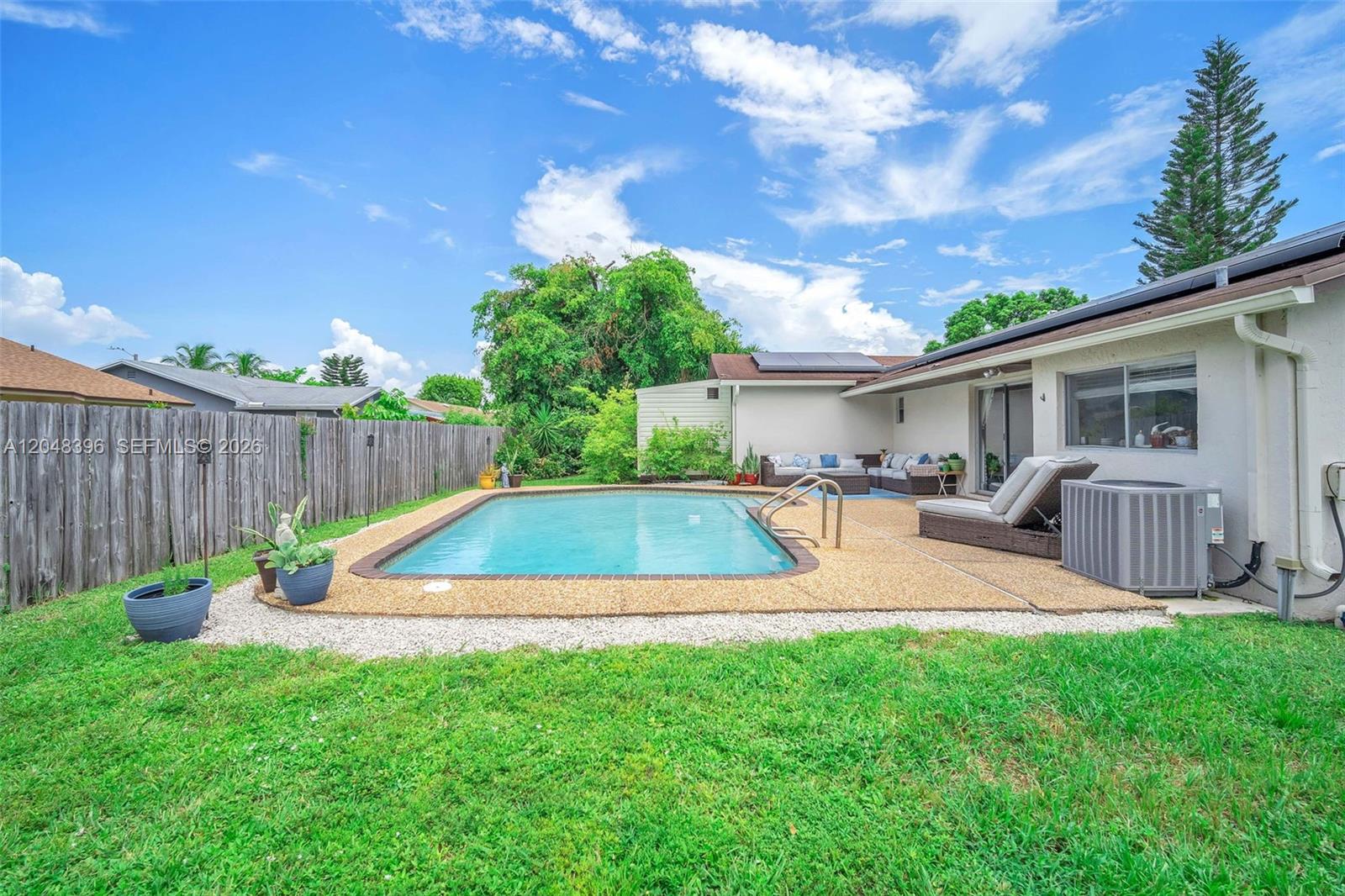 A backyard features a rectangular swimming pool, a patio area, and a wooden fence — 2401 NW 110th Ter # 2401, Sunrise FL 33322, SUNRISE, FL