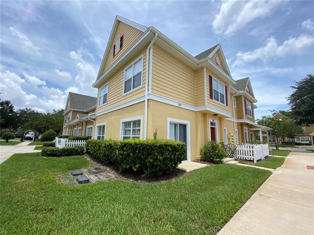 A yellow two-story townhouse with white trim and a white picket fence — 4552 JONAFREE LANE UNIT 101, KISSIMMEE, FL