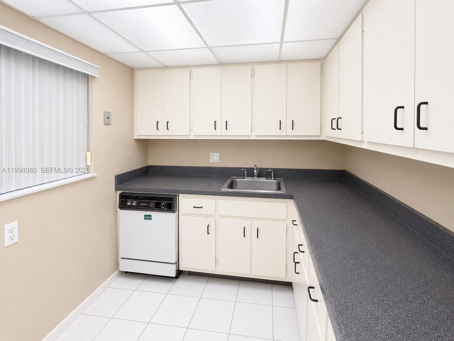A kitchen features white cabinets, a dark gray countertop, a dishwasher, and a stainless sink — 7787 SW 86th St # 206, Miami FL 33143, MIAMI, FL