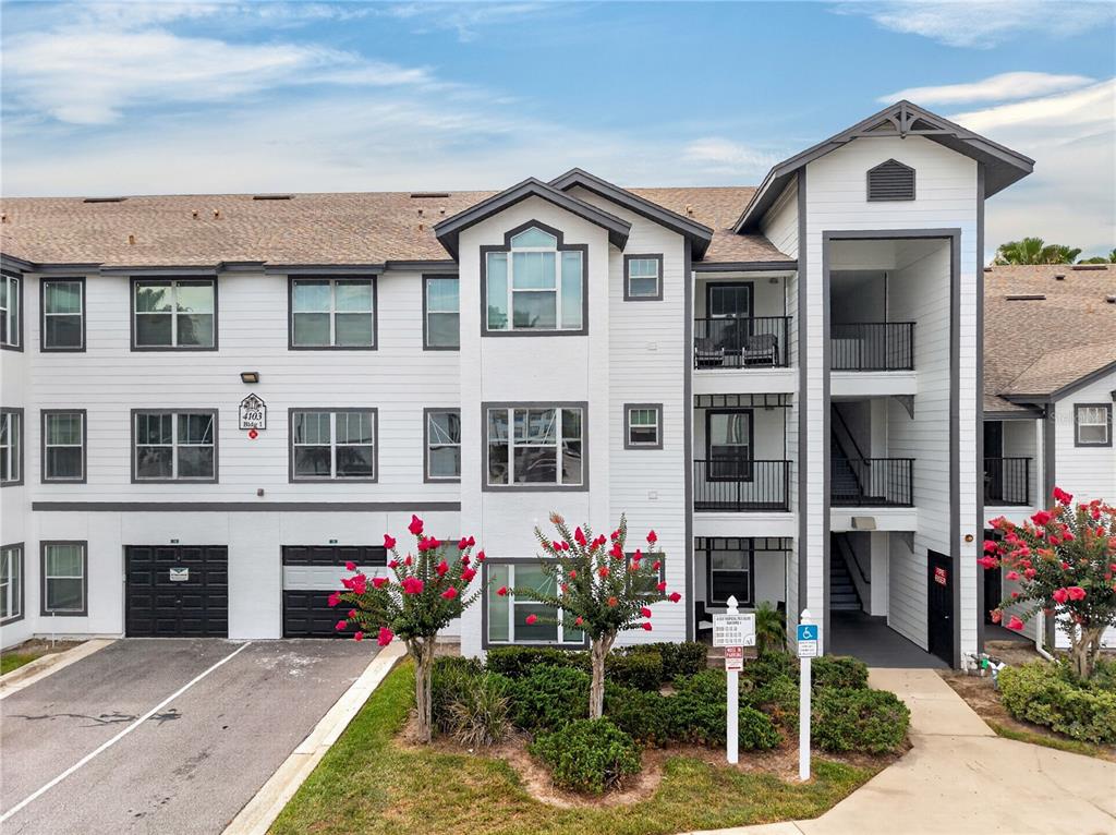 A three-story apartment building with white siding, dark trim, and a covered stairwell entrance — 4103 TROPICAL ISLE BLVD UNIT 123, KISSIMMEE, FL