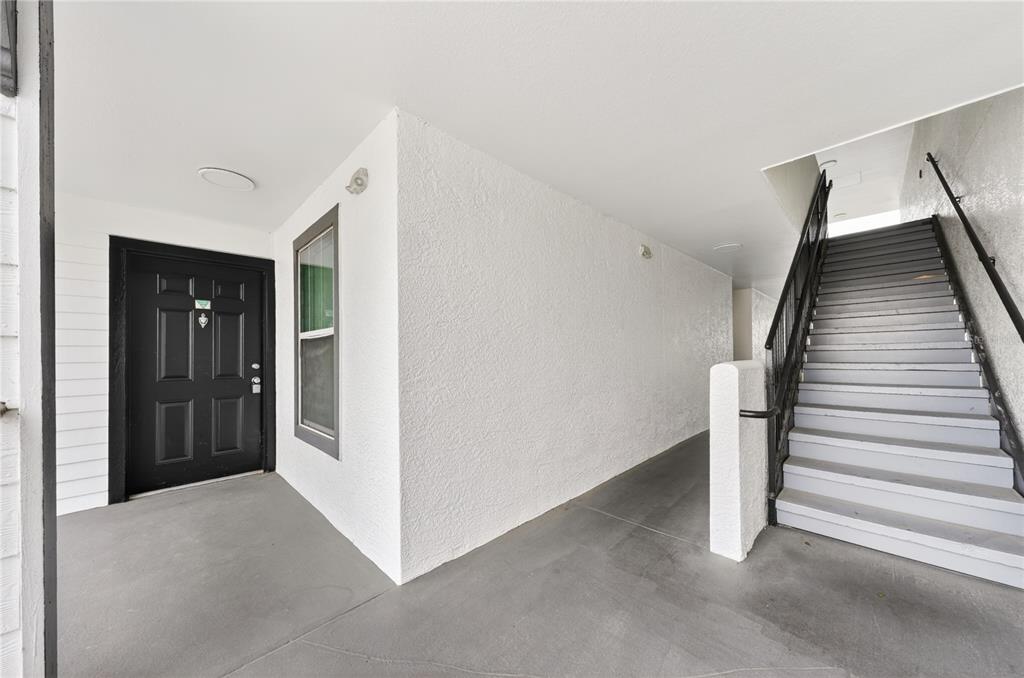 A black front door sits next to a staircase leading to an upper level — 4103 TROPICAL ISLE BLVD UNIT 123, KISSIMMEE, FL