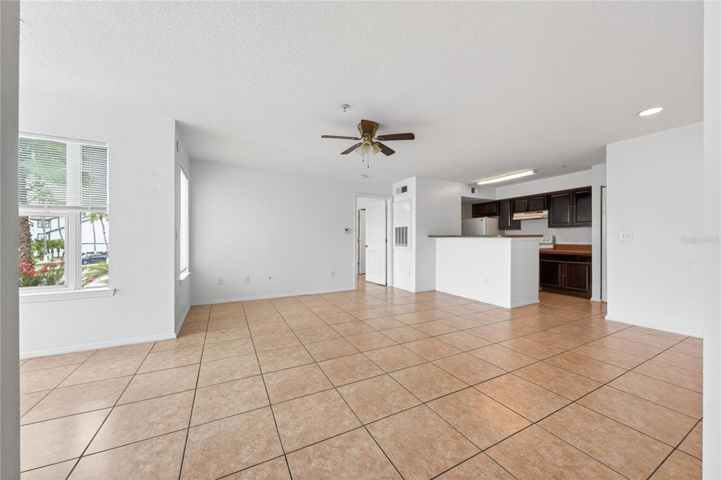 An open-concept living area features tan tile flooring, white walls, and a kitchen with dark cabinets — 4103 TROPICAL ISLE BLVD UNIT 123, KISSIMMEE, FL