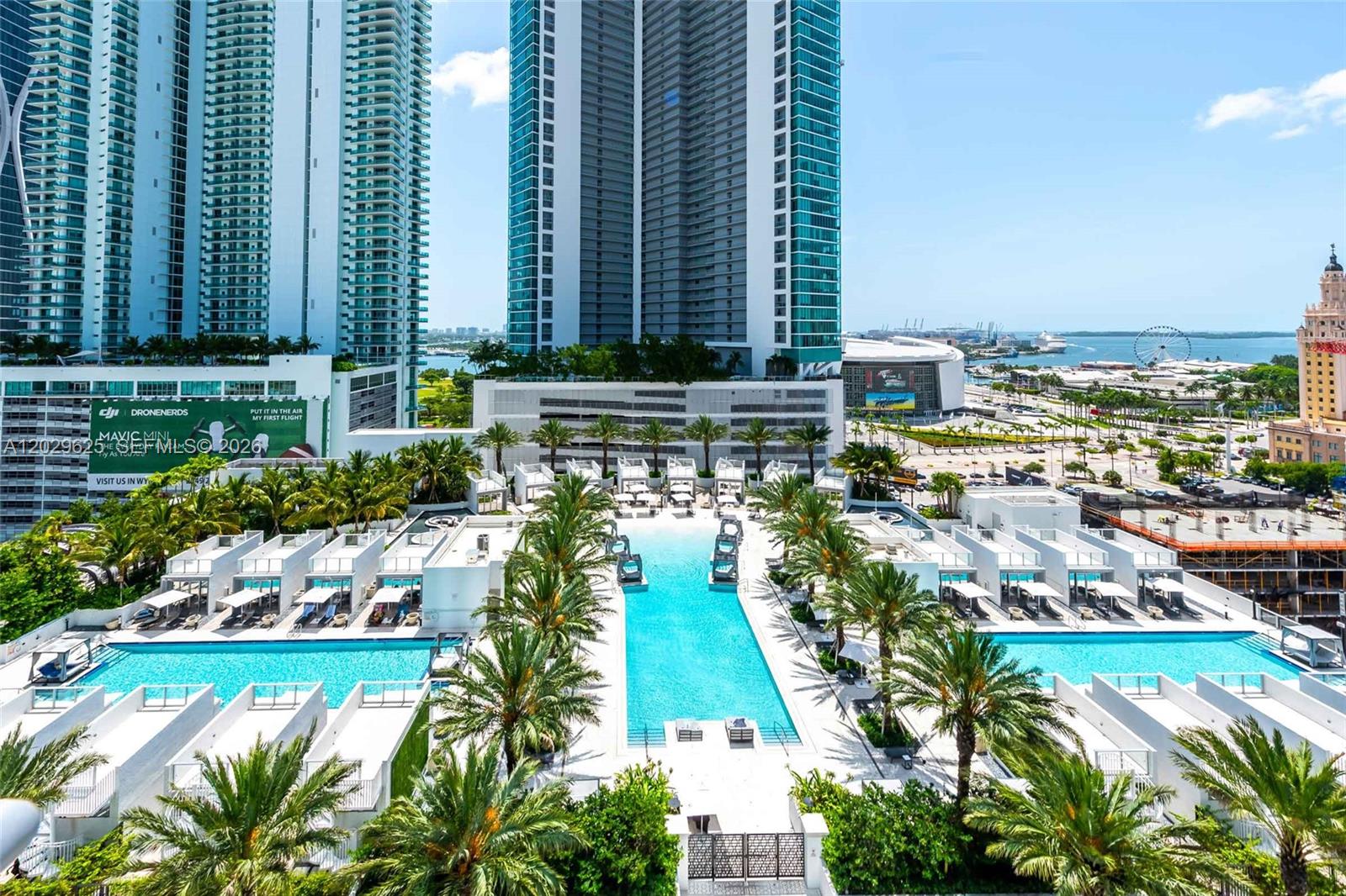 An aerial view of a large outdoor swimming pool surrounded by palm trees and buildings — 851 NE 1st Ave # 1705, Miami FL 33132, MIAMI, FL