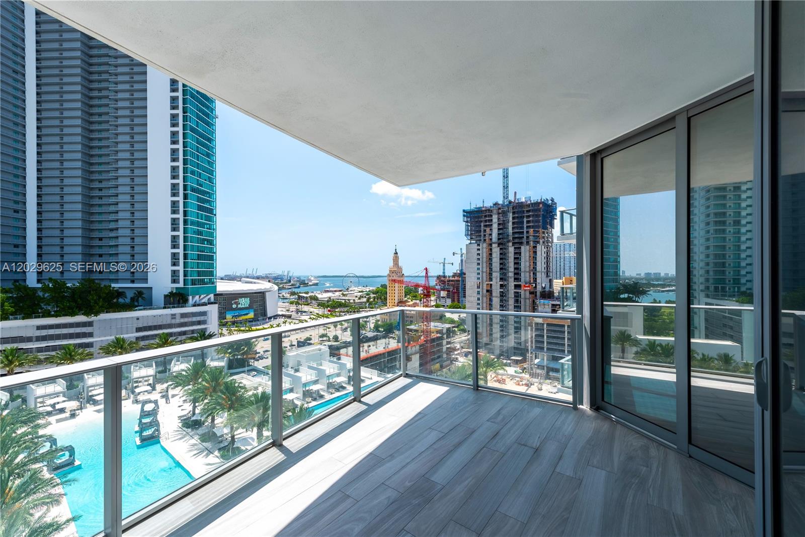 A balcony with wood-look tile flooring overlooks a swimming pool and a city skyline — 851 NE 1st Ave # 1705, Miami FL 33132, MIAMI, FL
