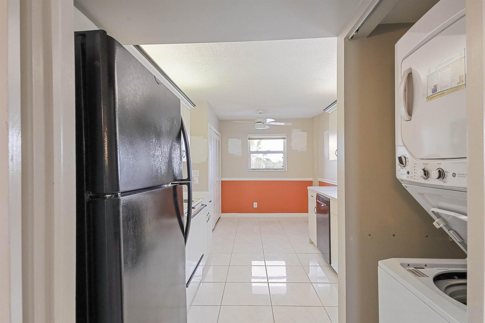 A kitchen with white tile floors, orange wainscoting, and a black refrigerator and dishwasher — 6850 10th Avenue N # 406, FL 33467, FL