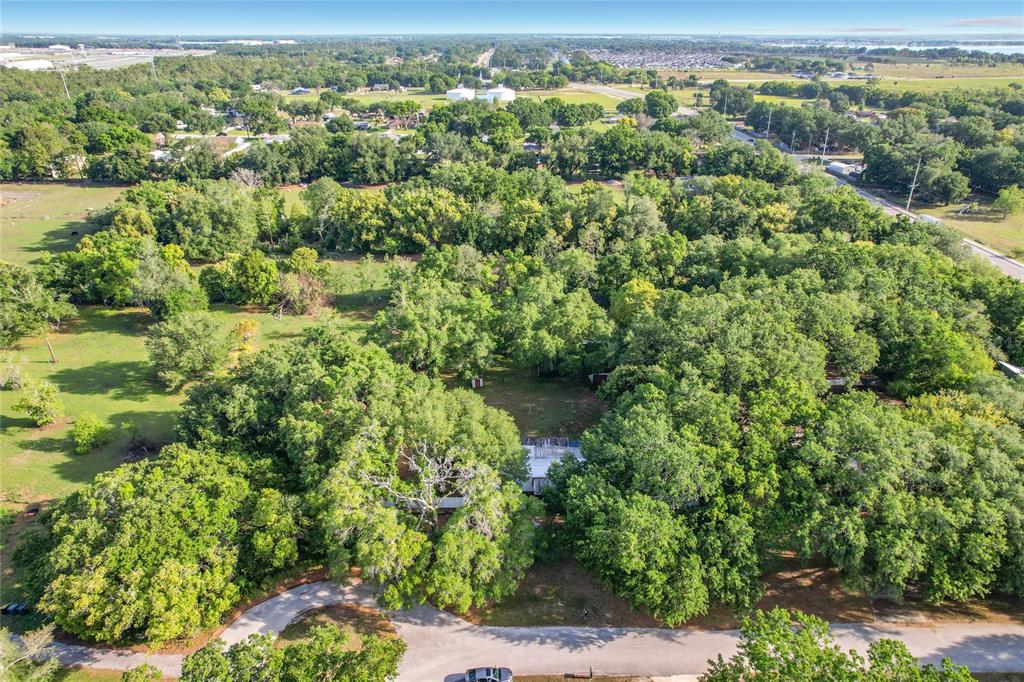 An aerial view shows a house nestled within a dense, wooded lot — 821 IRENE DRIVE, AUBURNDALE, FL