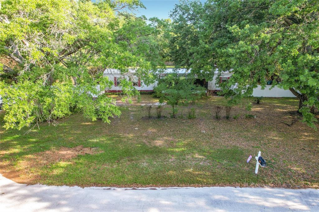 A single-story manufactured home sits on a grassy lot shaded by several large trees — 821 IRENE DRIVE, AUBURNDALE, FL