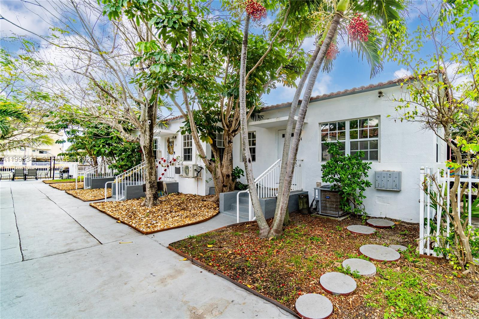 A white, single-story multi-unit building with palm trees, gravel landscaping, and a concrete walkway — 8335 E Crespi Blvd # 4, Miami Beach FL 33141, MIAMI BEACH, FL