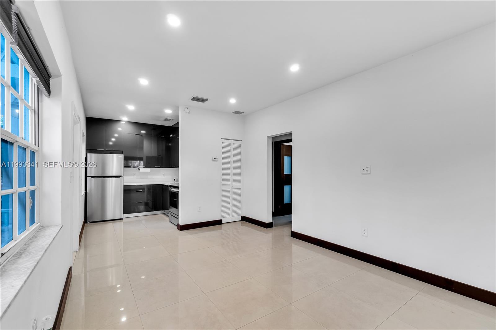 A kitchen with dark cabinets and stainless steel appliances opens into a tiled living area — 8335 E Crespi Blvd # 4, Miami Beach FL 33141, MIAMI BEACH, FL