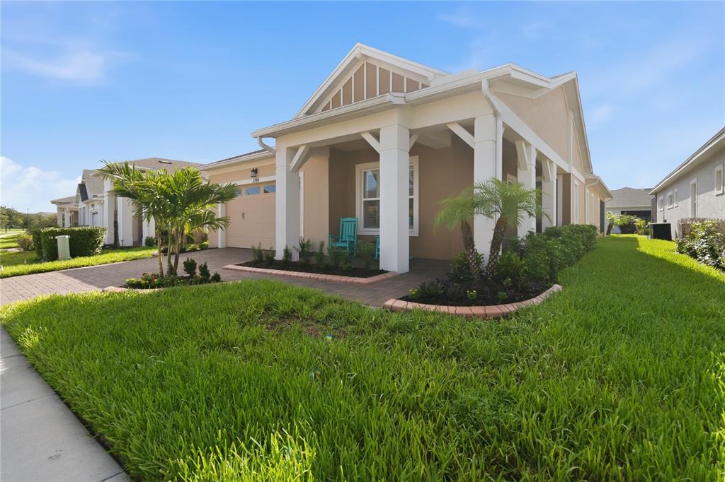 A tan single-story house with a covered front porch, white columns, and a paved driveway — 2789 SOUTHLAND STREET, ST CLOUD, FL