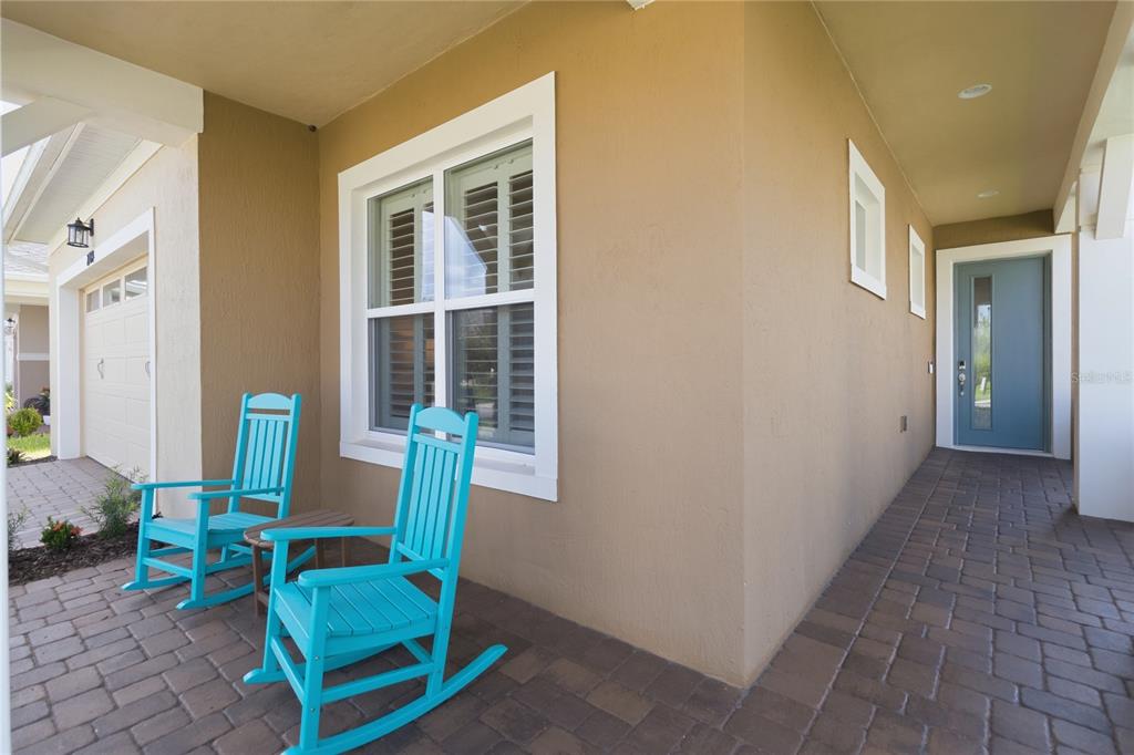 A covered front porch features two bright blue rocking chairs and a blue front door — 2789 SOUTHLAND STREET, ST CLOUD, FL