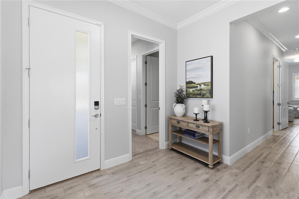 A bright entryway features a white front door, wood-look tile flooring, and a console table — 2789 SOUTHLAND STREET, ST CLOUD, FL