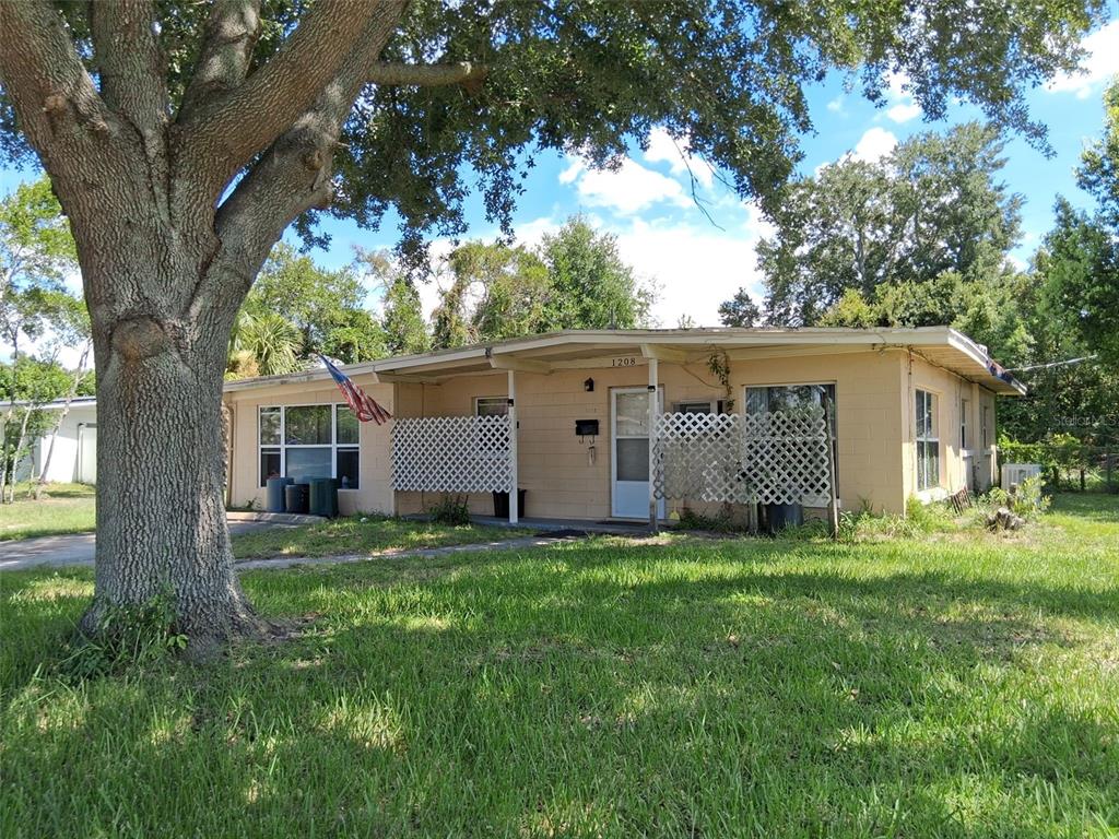 A single-story house with a tan exterior, lattice porch screens, and a large front tree — 1208 BEATRICE DRIVE, ORLANDO, FL