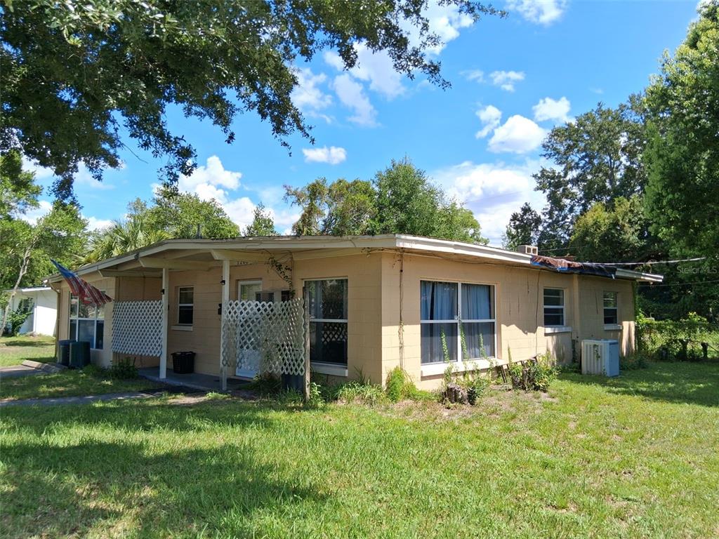 A single-story tan concrete block house with a covered front porch and lattice privacy screens — 1208 BEATRICE DRIVE, ORLANDO, FL