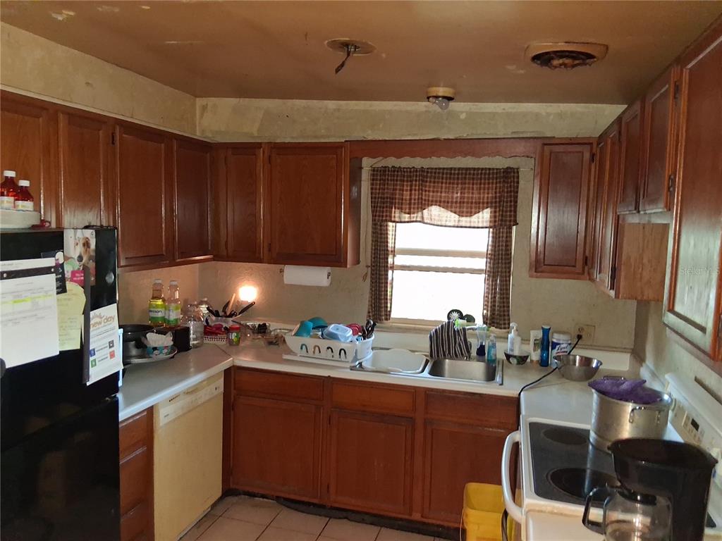 A kitchen with wood cabinets, laminate countertops, a double sink, and a window with curtains — 1208 BEATRICE DRIVE, ORLANDO, FL